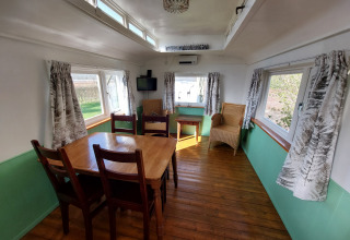 Comedor con mesa y sillas de madera en Pipowagen Snuf en Camping De Gouwe Stek, Países Bajos.