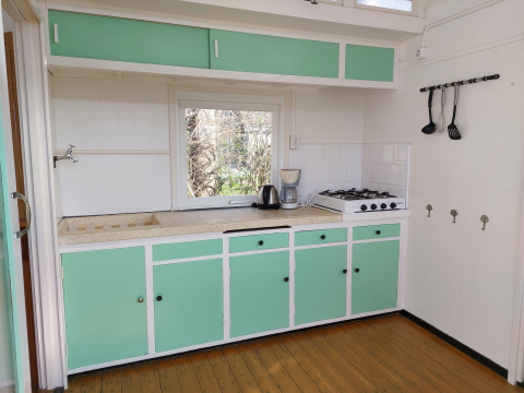 Acogedora cocina retro con armarios verde menta en Pipowagen Snuf, Camping De Gouwe Stek, Países Bajos.