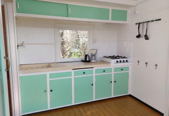 Acogedora cocina retro con armarios verde menta en Pipowagen Snuf, Camping De Gouwe Stek, Países Bajos.