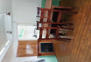 Interior de una cabaña en Pipowagen Snuf, Camping De Gouwe Stek, Países Bajos, con suelo y muebles de madera.