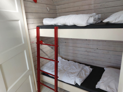 Habitación con litera y escalera roja en Pipowagen Snuf, Camping De Gouwe Stek, Países Bajos.