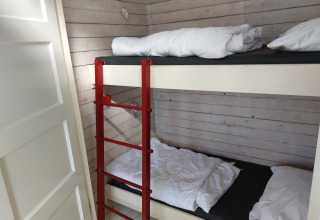 Habitación con litera y escalera roja en Pipowagen Snuf, Camping De Gouwe Stek, Países Bajos.