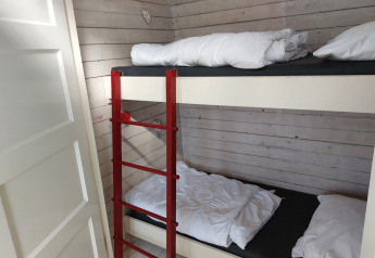 Habitación con litera y escalera roja en Pipowagen Snuf, Camping De Gouwe Stek, Países Bajos.
