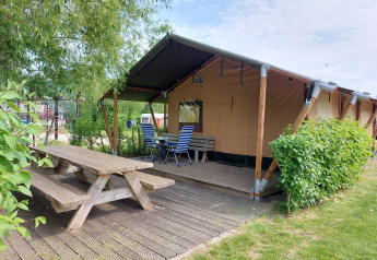 Tienda safari Glamping Ekster en Camping De Gouwe Stek, Países Bajos, con terraza de madera y bancos.