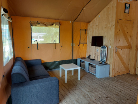 Interior de la tienda Glamping Safari Ekster en Camping De Gouwe Stek en los Países Bajos, con muebles cómodos.