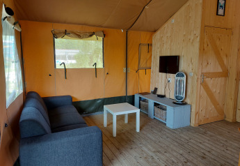 Interior de la tienda Glamping Safari Ekster en Camping De Gouwe Stek en los Países Bajos, con muebles cómodos.