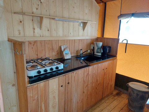 Keukengedeelte van een glamping safaritent met fornuis, gootsteen en koffiezet bij Camping De Gouwe Stek.