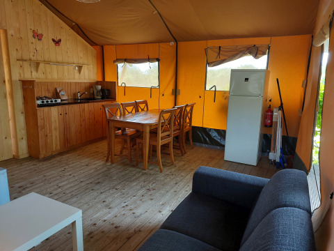 Indretning af Glamping Safari-telt Ekster med køkken, spisebord, sofa og køleskab på Camping De Gouwe Stek.