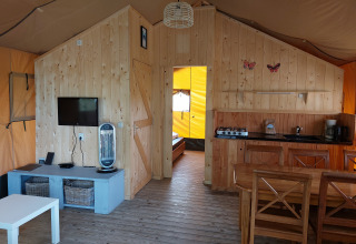 Interior de la tienda Glamping Safari Ekster en Camping De Gouwe Stek, con decoración de madera y comodidades.
