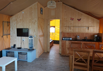 Intérieur de la tente Glamping Safari Ekster au Camping De Gouwe Stek, décor bois et équipements modernes.