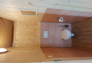 Badkamer met houten bekleding, toilet, borstel en papier in Glamping Safari tent Ekster, Nederland.