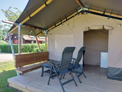 Tienda safari Merel en Camping De Gouwe Stek, Países Bajos, con veranda, sillas y una pequeña mesa.