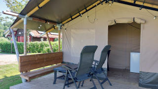 Tienda safari Merel en Camping De Gouwe Stek, Países Bajos, con veranda, sillas y una pequeña mesa.