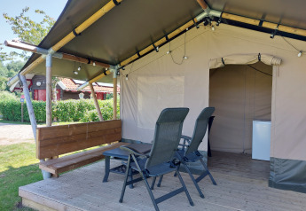 Tienda safari Merel en Camping De Gouwe Stek, Países Bajos, con veranda, sillas y una pequeña mesa.