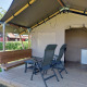 Tienda safari Merel en Camping De Gouwe Stek, Países Bajos, con veranda, sillas y una pequeña mesa.