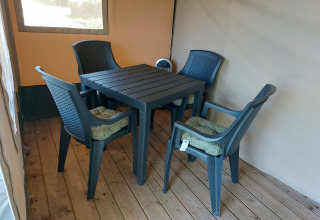 Udendørs siddeområde med fire plastikstole og et bord i Safari tent Merel på Camping De Gouwe Stek, Holland.