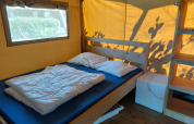 Habitación de lodge interior con cama doble, cojines blancos, estantería de madera y ventana amplia.