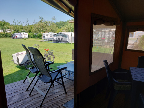 Vista desde la tienda Safari Merel en Camping De Gouwe Stek en Países Bajos, con caravanas y bicicleta.