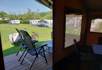 Vista dalla tenda Safari Merel al Camping De Gouwe Stek nei Paesi Bassi, con roulotte e bicicletta fuori.