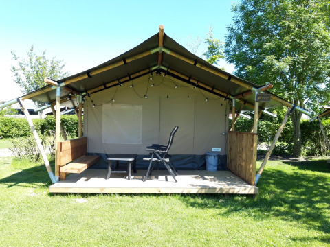 En safari-telt lodge ved Camping De Gouwe Stek i Holland med terrasse, stole og træbænk udenfor.