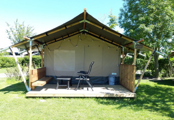 Safaritent Merel bij Camping De Gouwe Stek in Nederland met veranda, zitplaatsen en houten bankje.