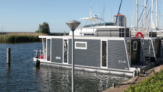 Woonboot Havenlodge Lelystad aangemeerd aan Marina Parcs Lelystad, omringd door water en boten in Nederland.