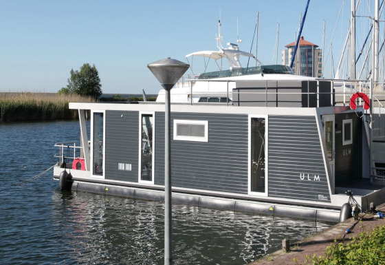 Casa flotante Havenlodge Lelystad amarrada en Marina Parcs Lelystad, rodeada de agua y barcos en Países Bajos.