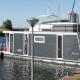 Husbåd Havenlodge Lelystad fortøjet ved Marina Parcs Lelystad, omgivet af vand og både i Holland.