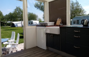 Cocina y área de descanso exterior en Glamping Pipowagen Klukkluk de Camping De Gouwe Stek en los Países Bajos.