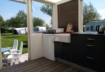 Cocina y área de descanso exterior en Glamping Pipowagen Klukkluk de Camping De Gouwe Stek en los Países Bajos.