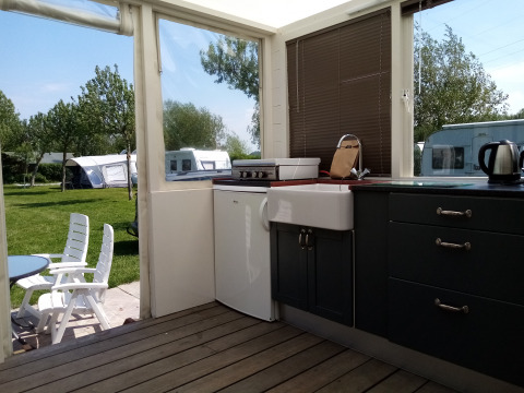 Cocina y área de descanso exterior en Glamping Pipowagen Klukkluk de Camping De Gouwe Stek en los Países Bajos.