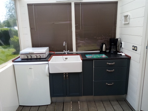 Área de cocina en Glamping Pipowagen Klukkluk con fregadero, nevera pequeña, cafetera y tetera.