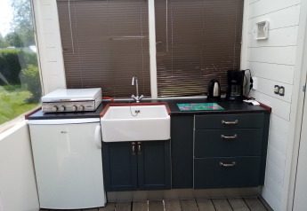 Área de cocina en Glamping Pipowagen Klukkluk con fregadero, nevera pequeña, cafetera y tetera.