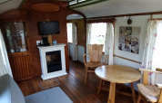 Interior de Glamping Pipowagen Klukkluk en Camping De Gouwe Stek, Países Bajos, con muebles y chimenea.