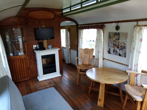 Interior de Glamping Pipowagen Klukkluk en Camping De Gouwe Stek, Países Bajos, con muebles y chimenea.