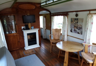 Interior de Glamping Pipowagen Klukkluk en Camping De Gouwe Stek, Países Bajos, con muebles y chimenea.