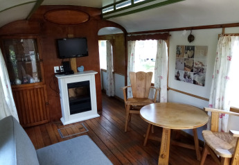 Interior de Glamping Pipowagen Klukkluk en Camping De Gouwe Stek, Países Bajos, con muebles y chimenea.
