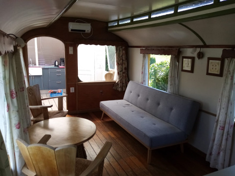 Interior del lodge Glamping Pipowagen Klukkluk con sofá, mesa y sillas en Camping De Gouwe Stek.