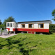 Afbeelding van Glamping Pipowagen Klukkluk met tuinmeubilair op een grasveld onder een blauwe lucht.