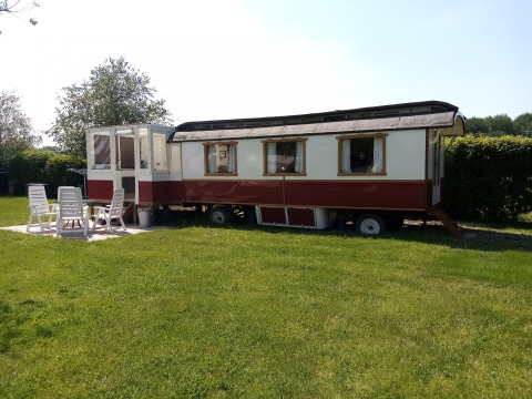 Glamping Pipowagen Klukkluk en Camping De Gouwe Stek, Países Bajos, con mesa y sillas de jardín al frente.