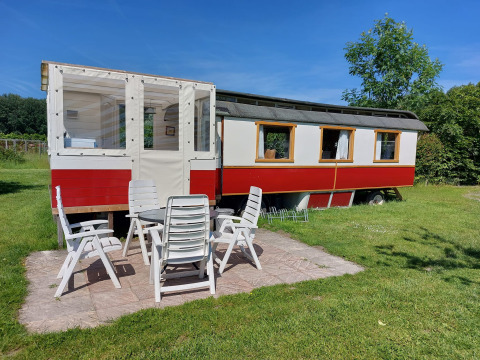 Vista exterior de Glamping Pipowagen Klukkluk en Camping De Gouwe Stek en los Países Bajos con sillas.