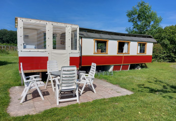 Vista exterior de Glamping Pipowagen Klukkluk en Camping De Gouwe Stek en los Países Bajos con sillas.