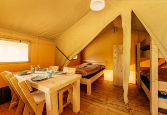 Binnenzicht van safaritent op Camping Braunlage in Duitsland met houten tafel, stoelen en stapelbed.