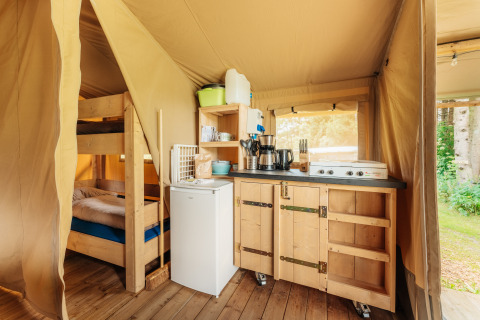 Vista interior de una tienda safari en Camping Braunlage, Alemania, con cocina y litera de madera.