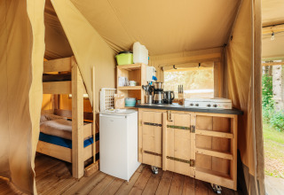 Vista interior de una tienda safari en Camping Braunlage, Alemania, con cocina y litera de madera.