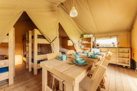 Interior view of Safari tent at Camping Braunlage in Germany with wooden furniture, kitchen and bunk beds.