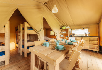 Innenansicht eines Safari-Zeltes auf Camping Braunlage in Deutschland mit Holzmöbeln und Kochnische.