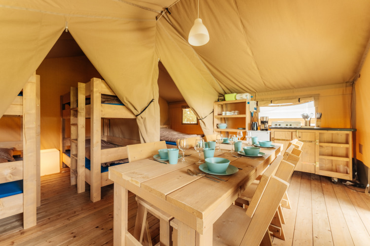 Vista interior de una tienda Safari en Camping Braunlage, Alemania, con muebles de madera y cocina equipada.