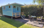 Casa rodante azul con terraza y muebles de jardín en Camping De Gouwe Stek, Países Bajos, con sol.
