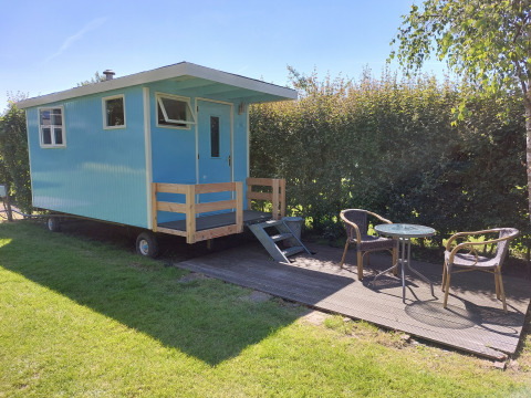 Casa rodante azul con terraza y muebles de jardín en Camping De Gouwe Stek, Países Bajos, con sol.